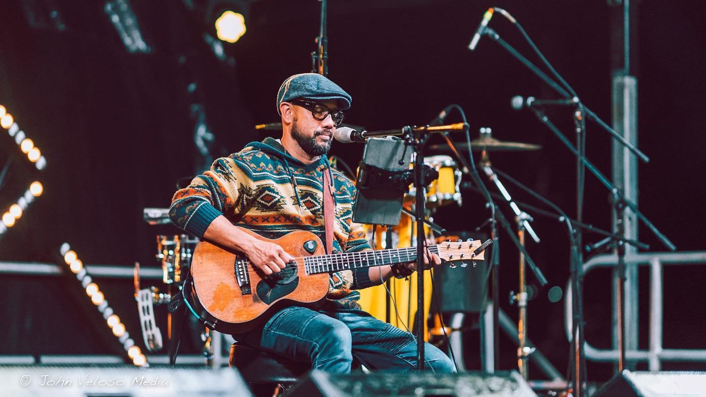 John playing acoustic guitar on a festival stage